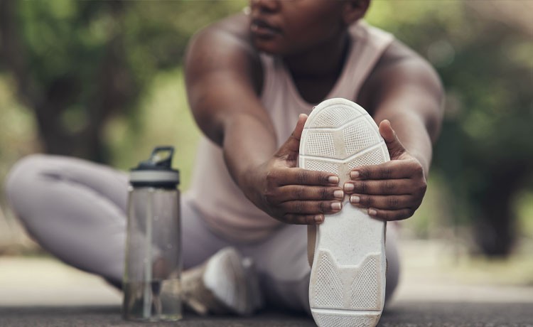 A young man stretches and keeps hydrated before an exercise session.
