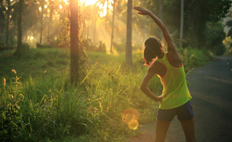 A woman prepares for a summer run in the forest.