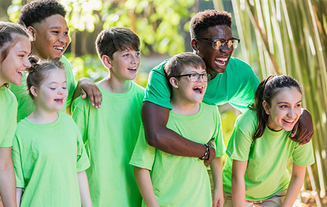 A group of children and their counselor gather outside in a group.