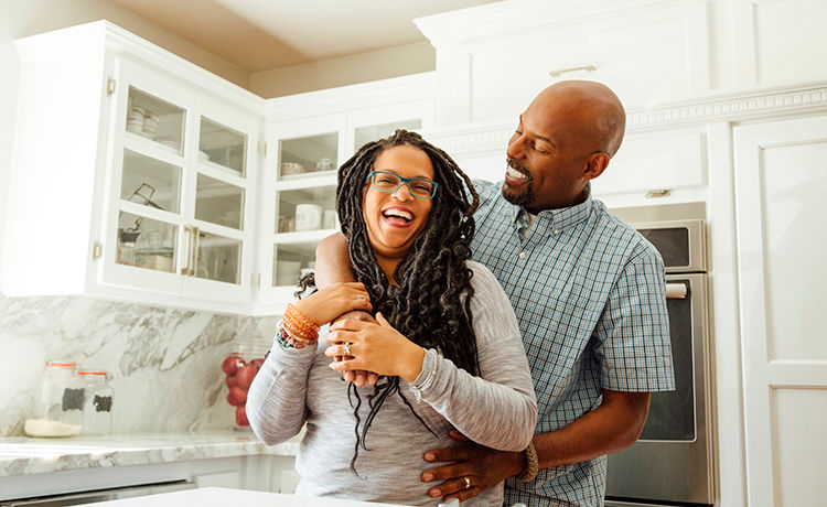 middle aged couple hugging and smiling in the kitchen
