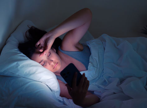 Woman lying in bed staring at her cellphone