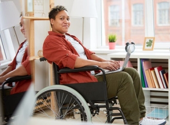 A woman in a wheelchair reads a mental health newsletter online.