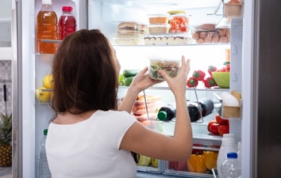 A woman gets healthy food out of her refrigerator.
