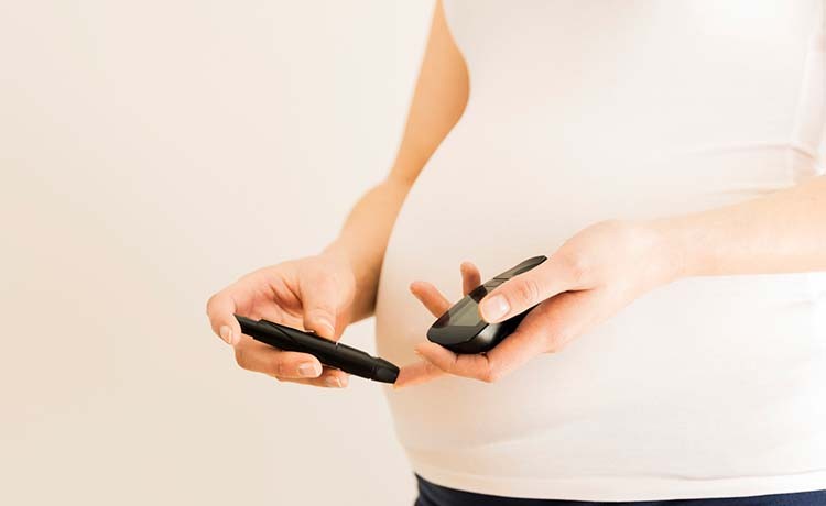 Pregnant woman tests her blood sugar.